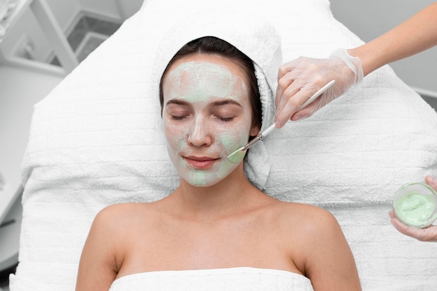 Beautician applying face mask on female client