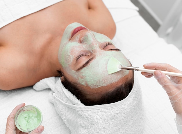 Beautician applying face mask on female client