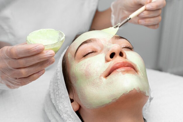 Beautician applying face mask on female client