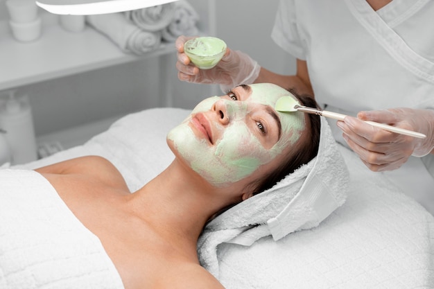 Beautician applying face mask on female client