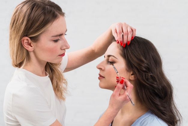 Beautician applying makeup to young woman 