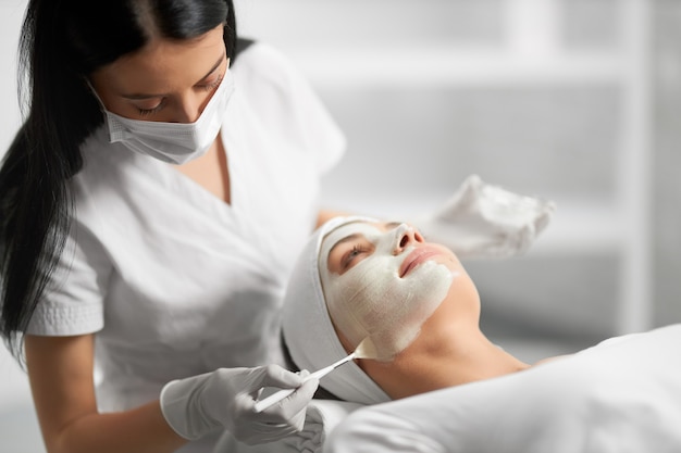 Beautician applying special white cream for patient