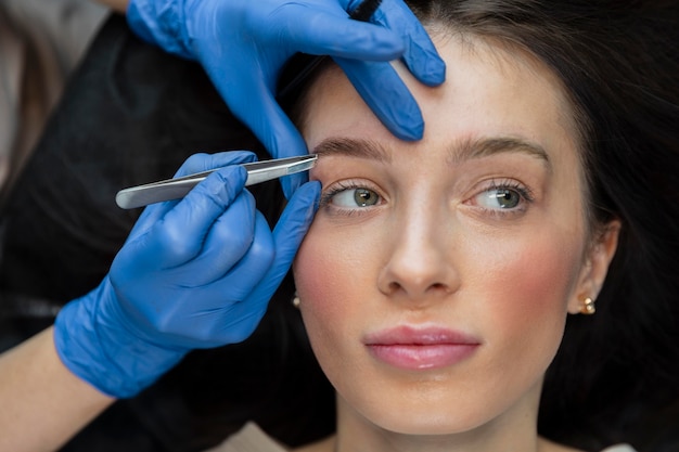 Beautician doing an eyebrow treatment for her female client