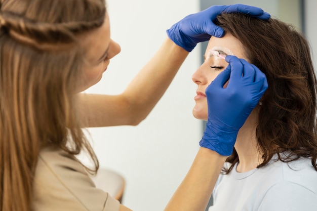 Beautician doing an eyebrow treatment for her female client