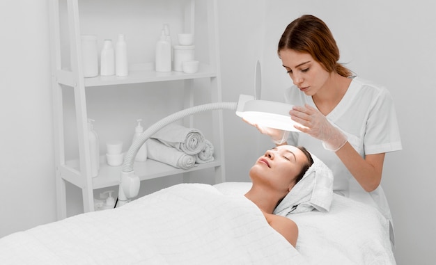 Free photo beautician doing face beauty routine for female client