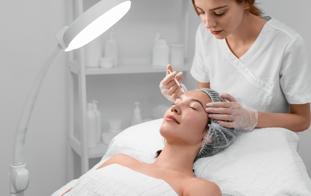 Beautician doing filler injection for female client