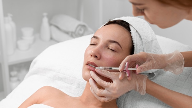 Beautician doing injection filler on female client