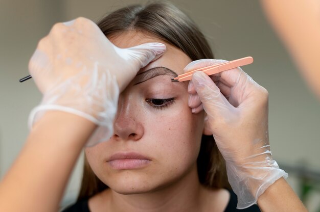 Beautician doing a microblading procedure on a young woman