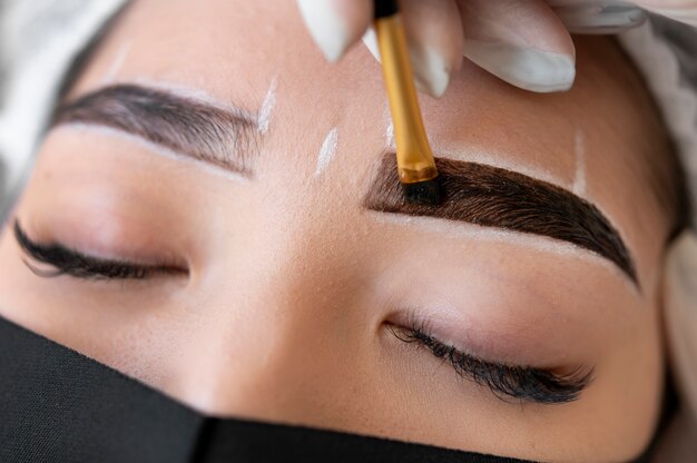 クライアントの眉毛にマイクロブレードトリートメントを行う美容師