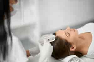 Free photo beautician in protective mask doing procedure for hair