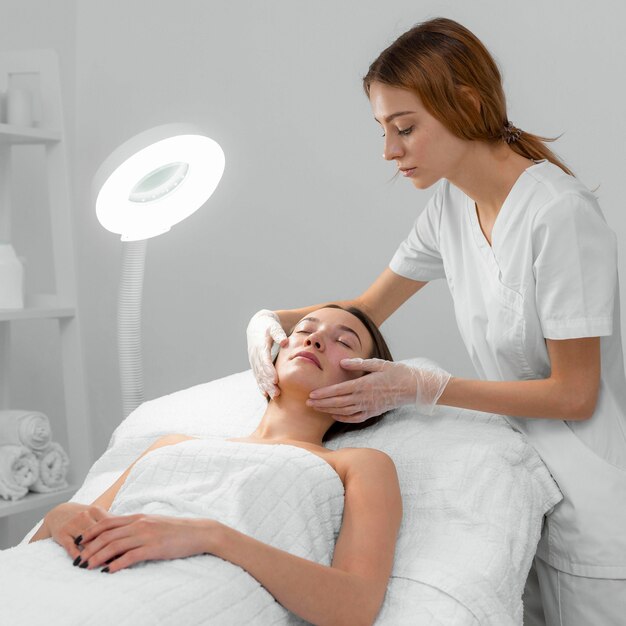 Beautician with female client at salon for face care routine