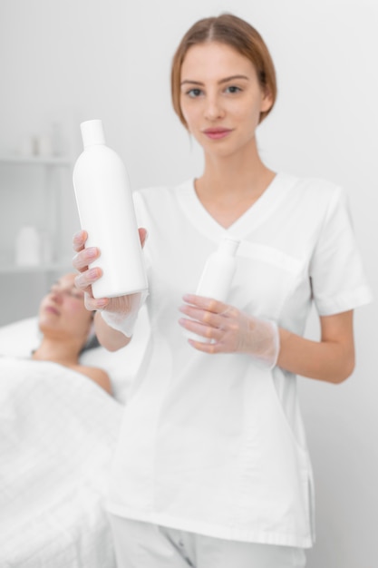 Beautician with lotion for female client