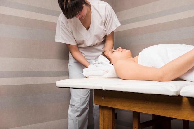 Beautician wrapping towel on woman's head