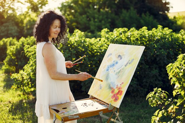 Beautiful adult woman drawing in a summer field