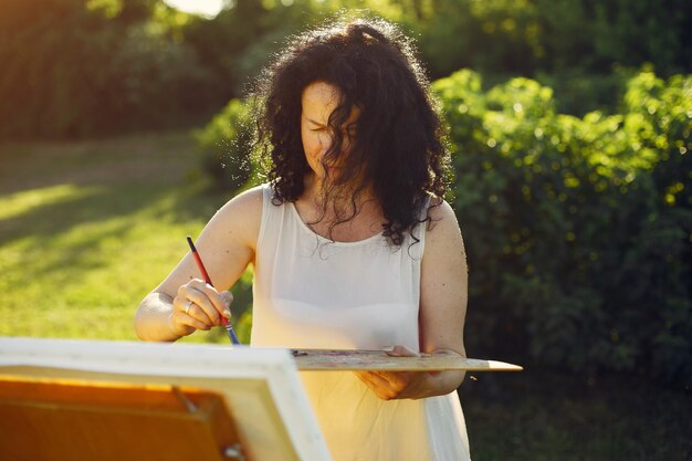 Beautiful adult woman drawing in a summer field