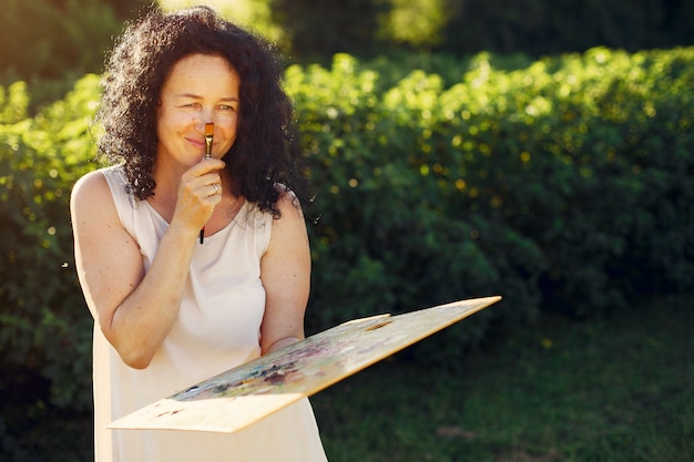 Beautiful adult woman drawing in a summer field