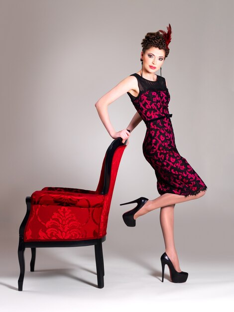 패션 헤어 스타일과 빨간 안락 의자와 아름다운 성인 여성이 스튜디오에서 포즈