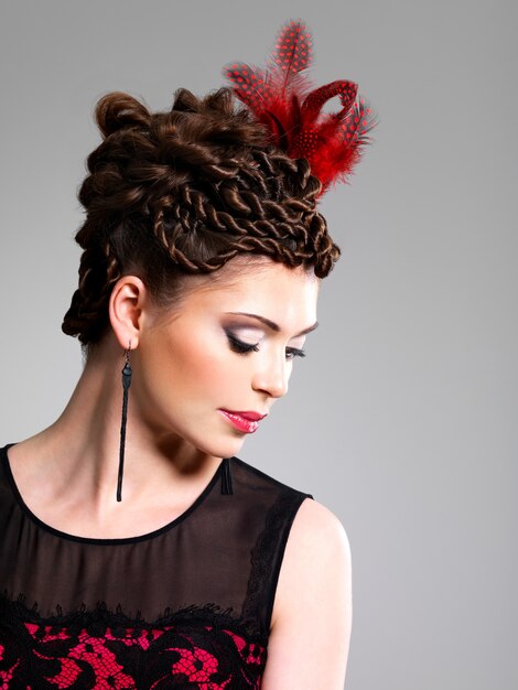 Beautiful adult woman with fashion hairstyle with red feather in hairs