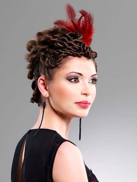 Beautiful adult woman with fashion hairstyle with red feather in hairs