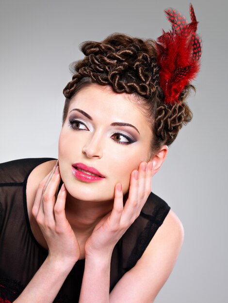 Beautiful adult woman with fashion hairstyle with red feather in hairs