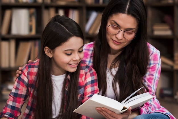 Free photo beautiful adult woman and young girl reading a book