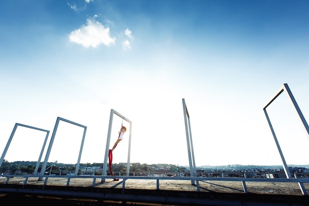 Beautiful aerial dancer, silk dance on roof at sunrise