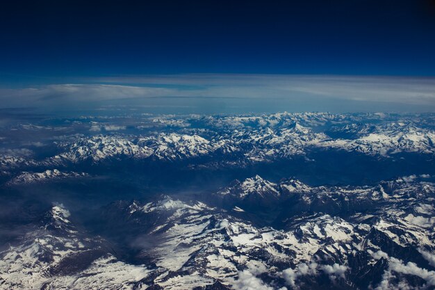 息をのむような青い空の下で雪に覆われた山岳風景の美しい空中ショット