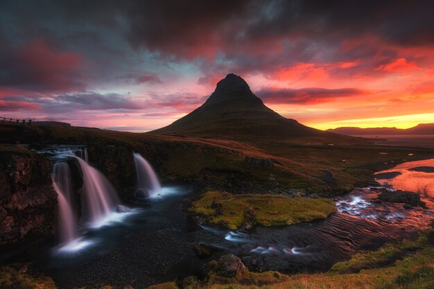 Beautiful aerial shot of a waterfall surrounded by hill at sunset