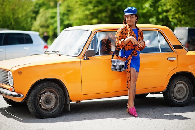 Красивая африканская американка, стоящая возле оранжевого классического ретро-автомобиля