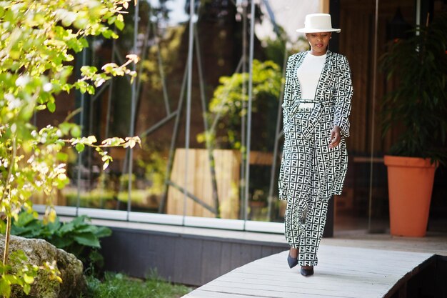 Beautiful african american woman natural makeup wear fashion clothes casual black and white dress code office style total blouse and pants suit and hat