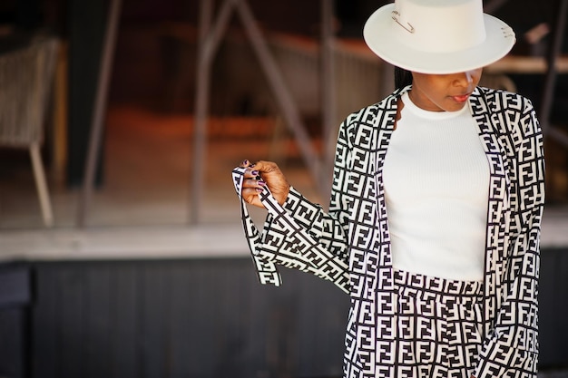 Free photo beautiful african american woman natural makeup wear fashion clothes casual black and white dress code office style total blouse and pants suit and hat