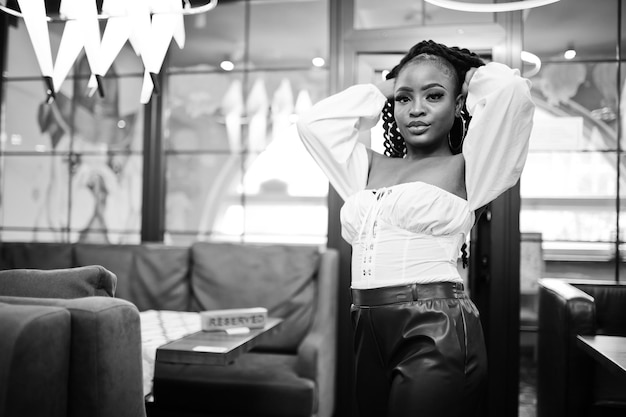 Free photo beautiful african american woman in white blouse and red leather pants pose at restaurant