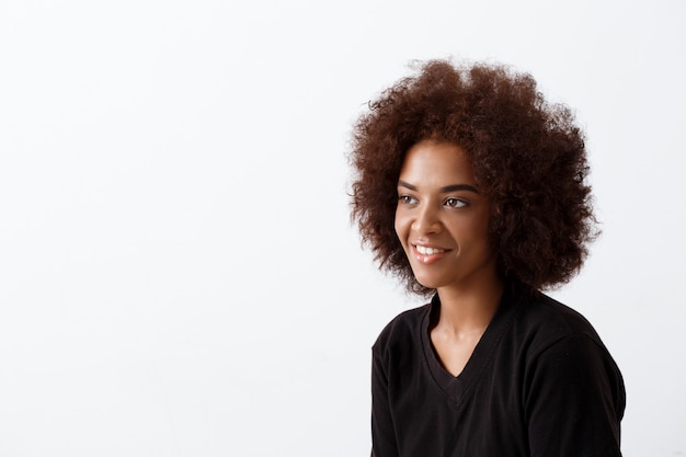 Beautiful african girl smiling over light wall.