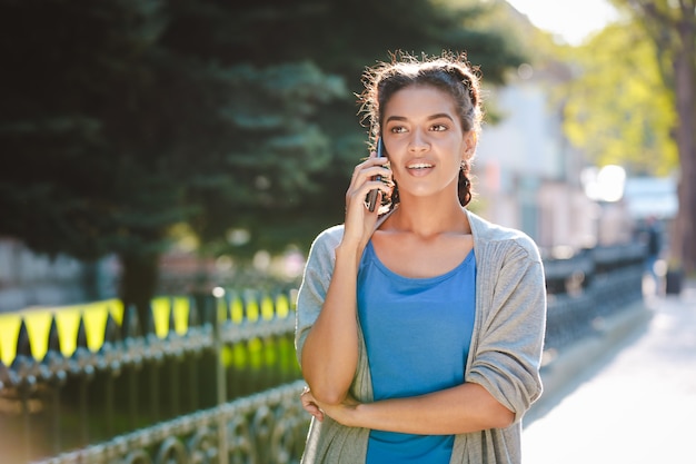 Bella ragazza africana che parla sul telefono al fondo della natura