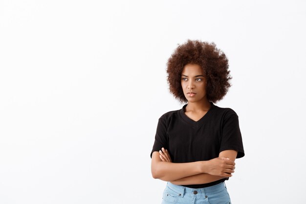 Beautiful african girl thinking over light wall.