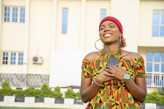 Beautiful African lady holding her phone to her chest filled with joy