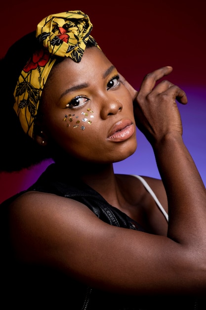 Free photo beautiful african woman in leather vest with shiny confetti on her cheeks