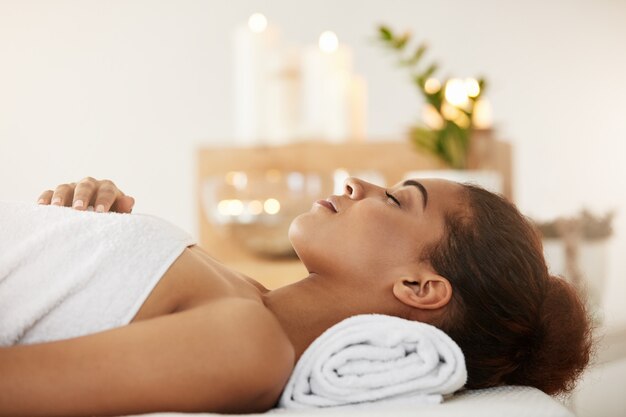 Beautiful african woman lying in spa salon