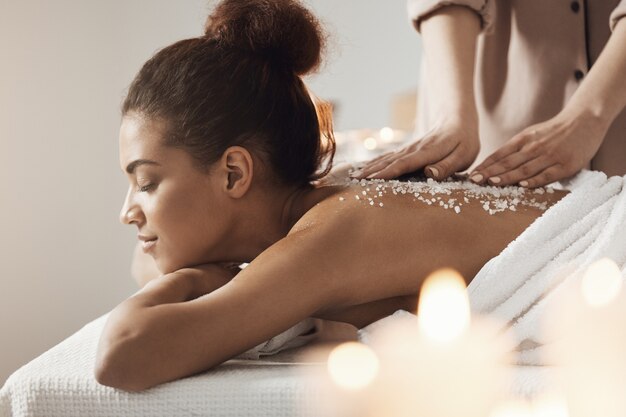 Beautiful african woman resting enjoying spa health massage with sea salt.