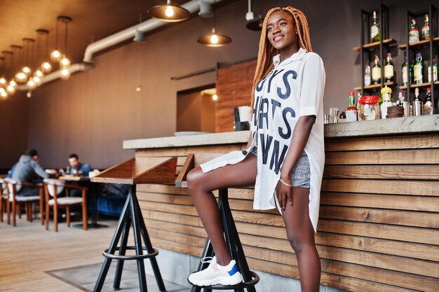 Beautiful african woman in stylish casual clothes posing near bar counter