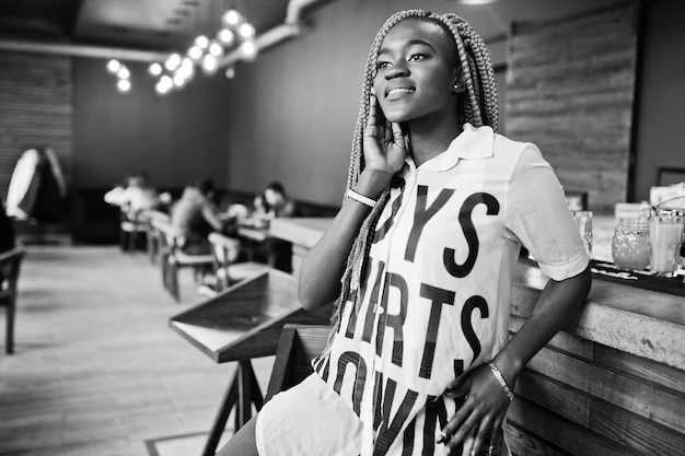 Beautiful african woman in stylish casual clothes sitting near bar counter