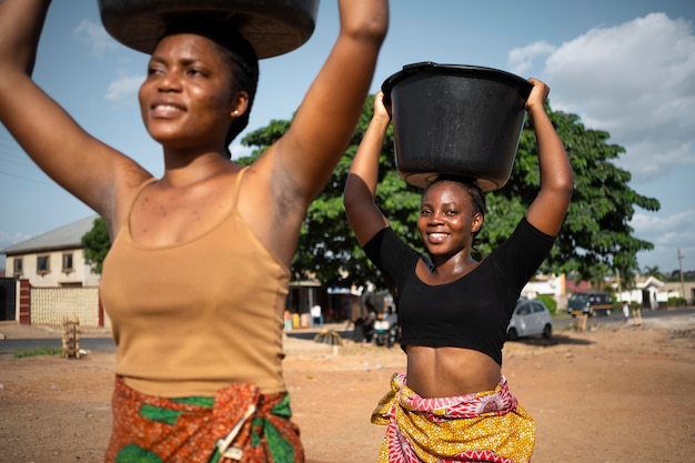 Free photo beautiful african women fetching water from outdoors