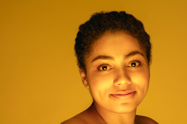 무료 사진 네온 불빛 단색의 노란색 스튜디오 배경에 격리된 아름다운 아프리카계 미국인 여성 초상화