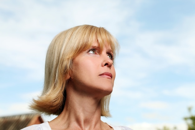 Beautiful aged woman over sky background