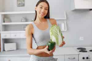 Бесплатное фото Красивая и спортивная женщина на кухне с овощами