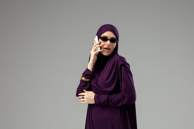 스튜디오에서 격리된 세련된 히잡을 입고 포즈를 취하는 아름다운 아랍 여성