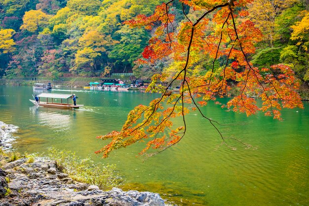 Beautiful Arashiyama river with maple leaf tree and boat around lake