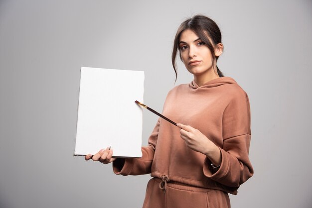 Beautiful artist posing with paint brush and canvas. 