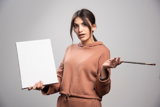 Free photo beautiful artist posing with paint brush and canvas.