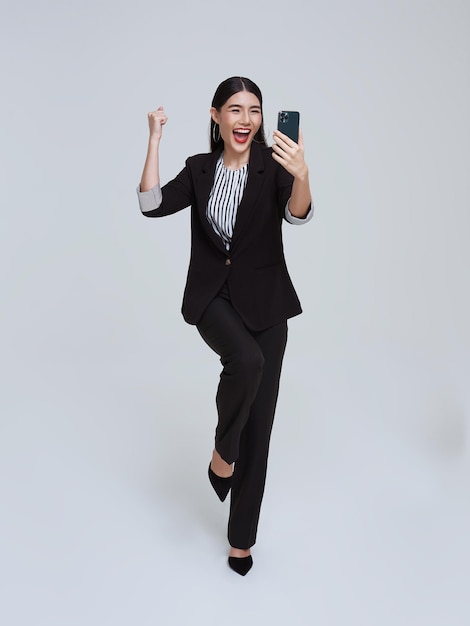 Красивая азиатская деловая женщина с мобильным телефоном и счастливым праздником на фоне белой студии